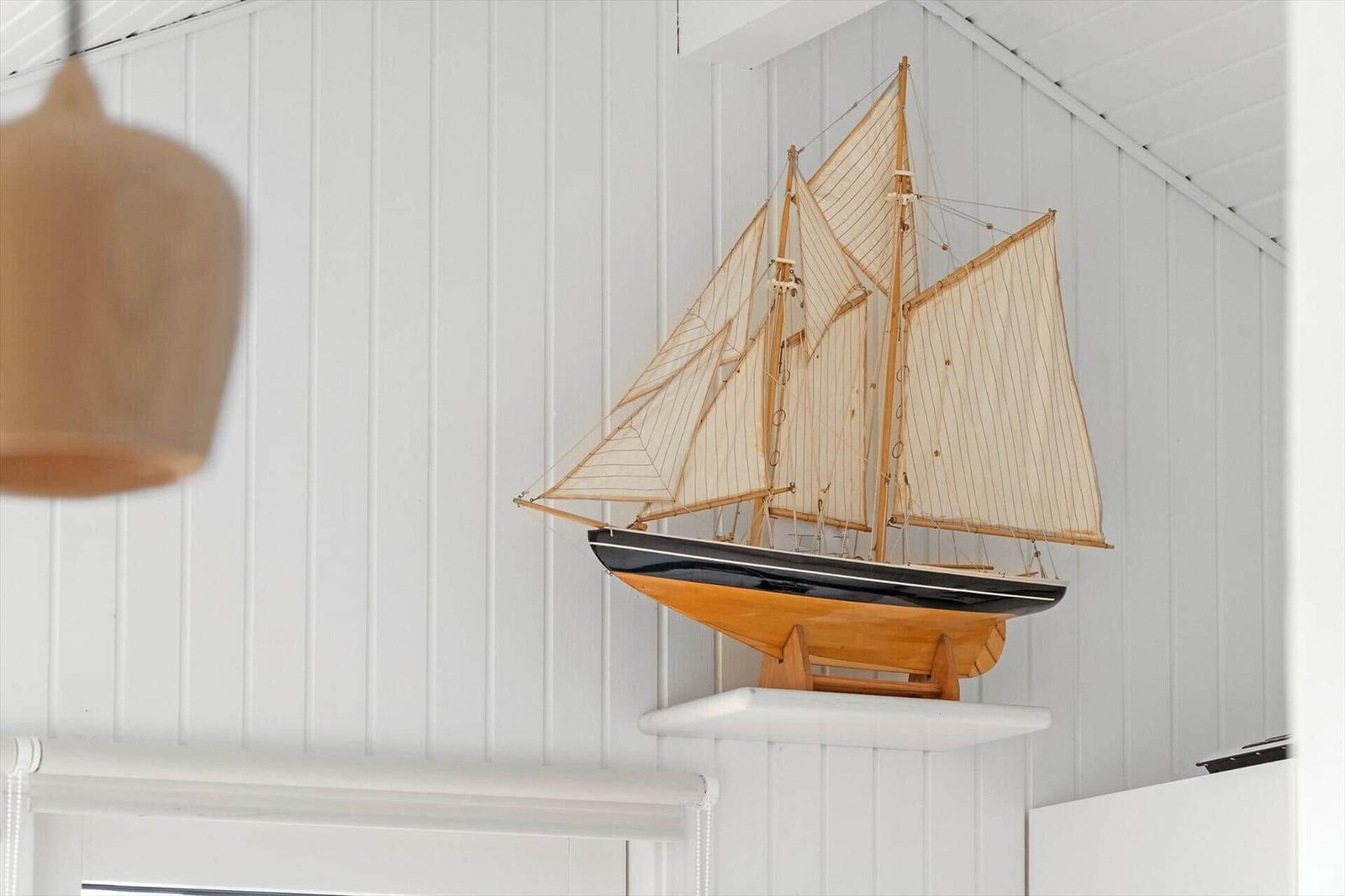 Ein hölzernes Segelschiffmodell steht auf einem weißen Sockel an der Wand.