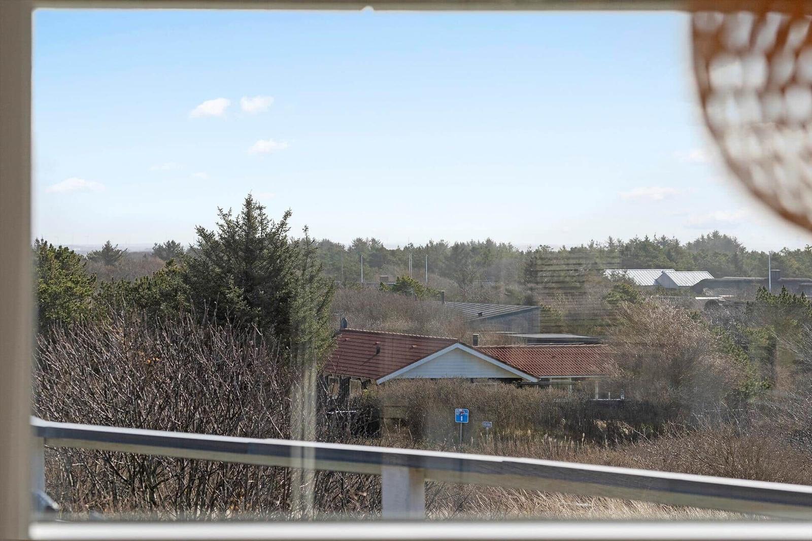 Blick aus dem Fenster auf Häuser und Bäume unter blauem Himmel.