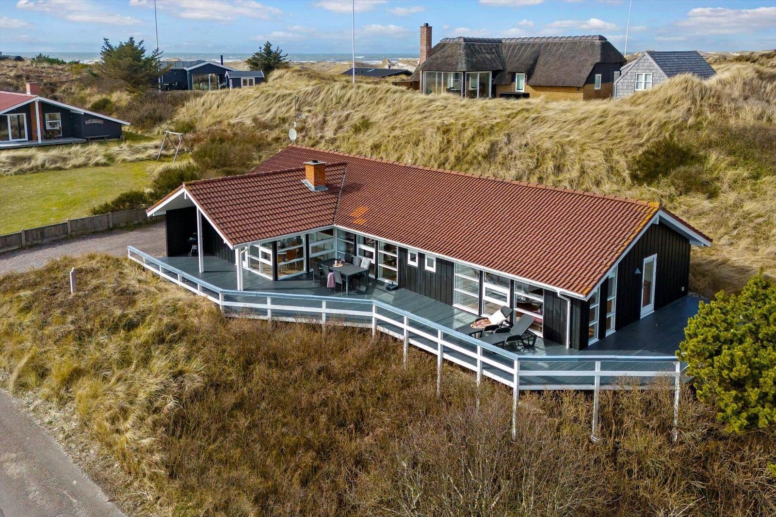 Moderne Villa mit Terrasse und Meerblick, umgeben von Dünen.
