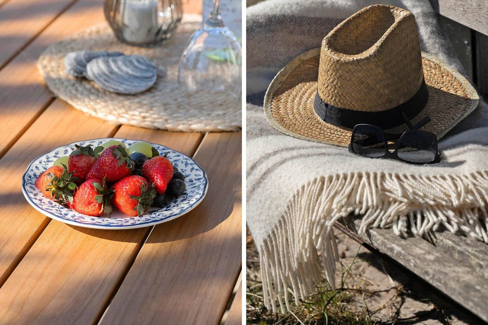 Eine Obstschale auf einer Terrasse und ein Strohhut mit Sonnenbrille auf einer Decke.