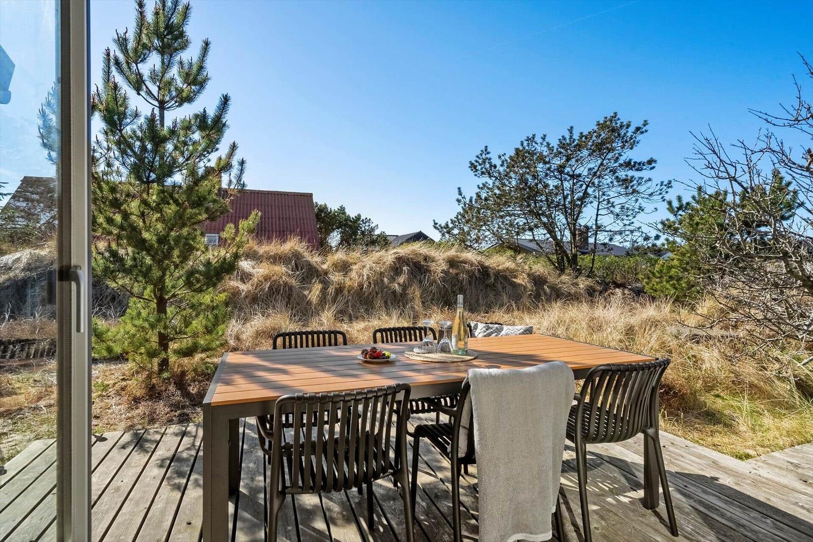 Terrasse mit Tisch und Stühlen, Blick auf Gras- und Bäume.