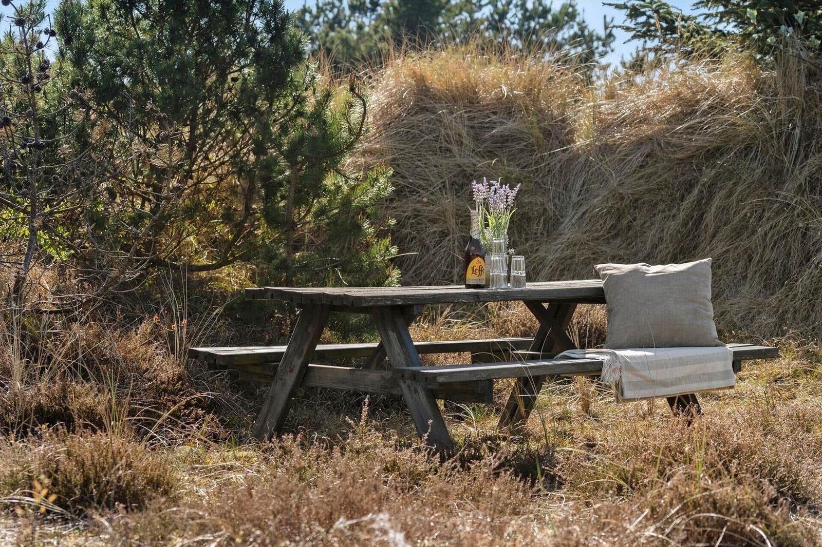 Holztisch mit Flasche, Gläsern und Lavendel im Gras.