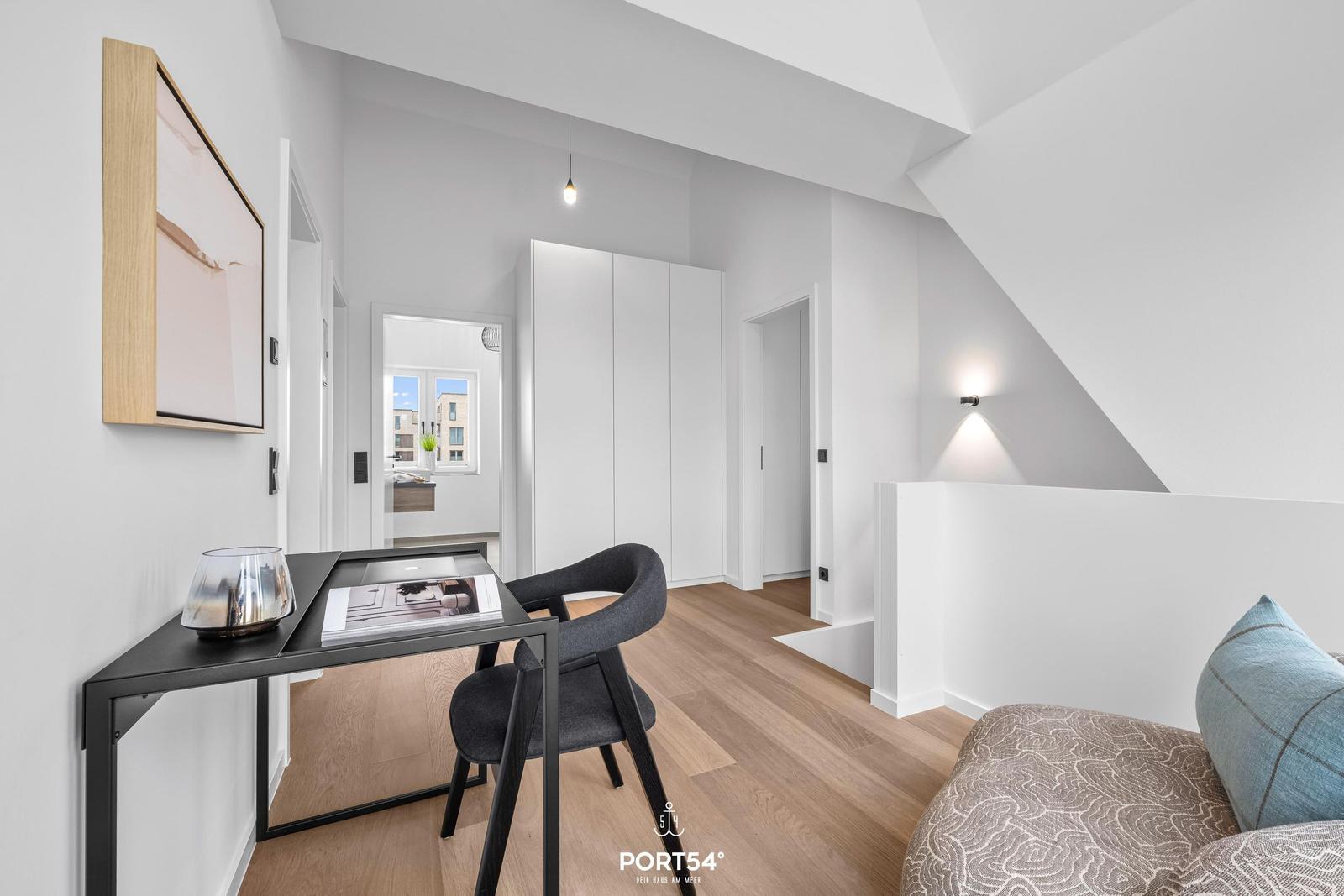 Schlafzimmer mit Schreibtisch, Bett und Kleiderschrank unter Dachschrägen.