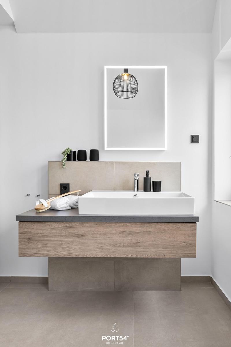 Moderne Badewanne mit Waschbecken, Spiegel und Hängelampe.