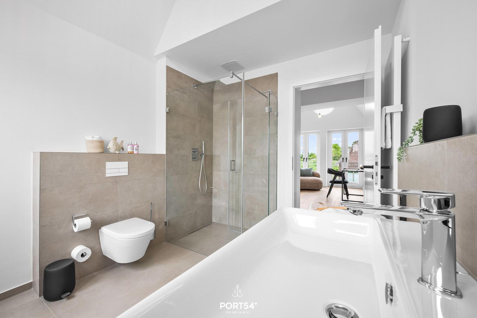 Badezimmer mit Dusche, Toilette und Badewanne. Durchgang zum Wohnbereich.