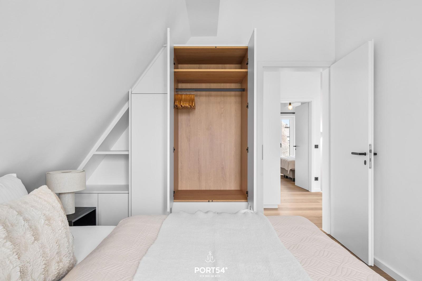 Schlafzimmer mit integriertem Kleiderschrank und Blick in den Flur.