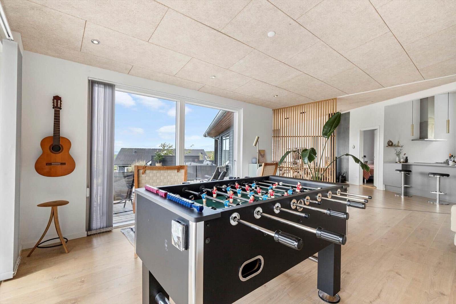 Fußballtisch im Wohnbereich mit Blick auf Terrasse und Küche.