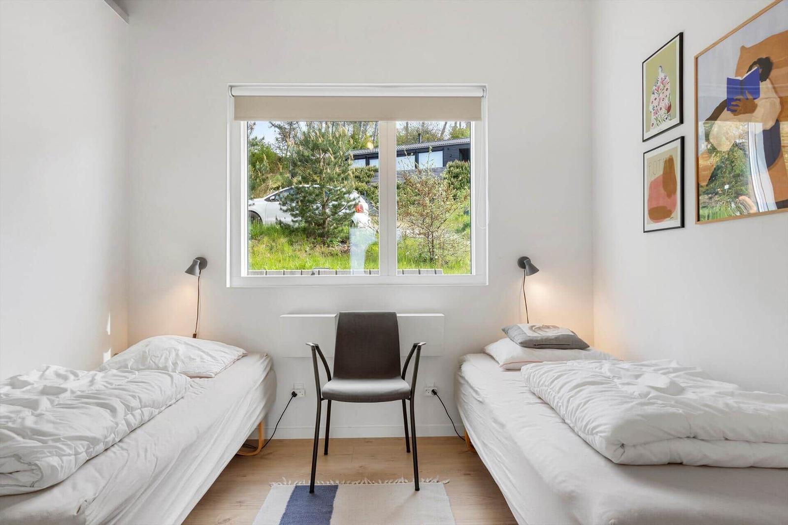 Zwei Einzelbetten, Stuhl und Fenster mit Blick auf Grünflächen.