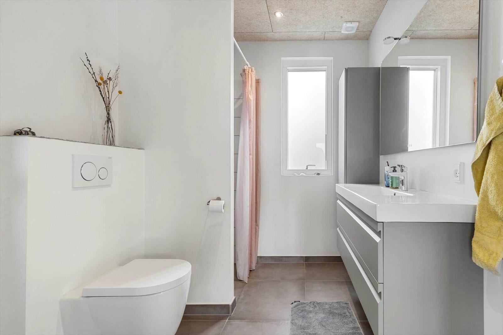 Badezimmer mit Toilette, Waschbecken und Dusche mit rosa Vorhang.