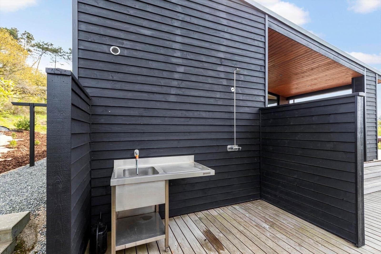 Außenbereich mit Waschbecken und Dusche an der Hauswand.