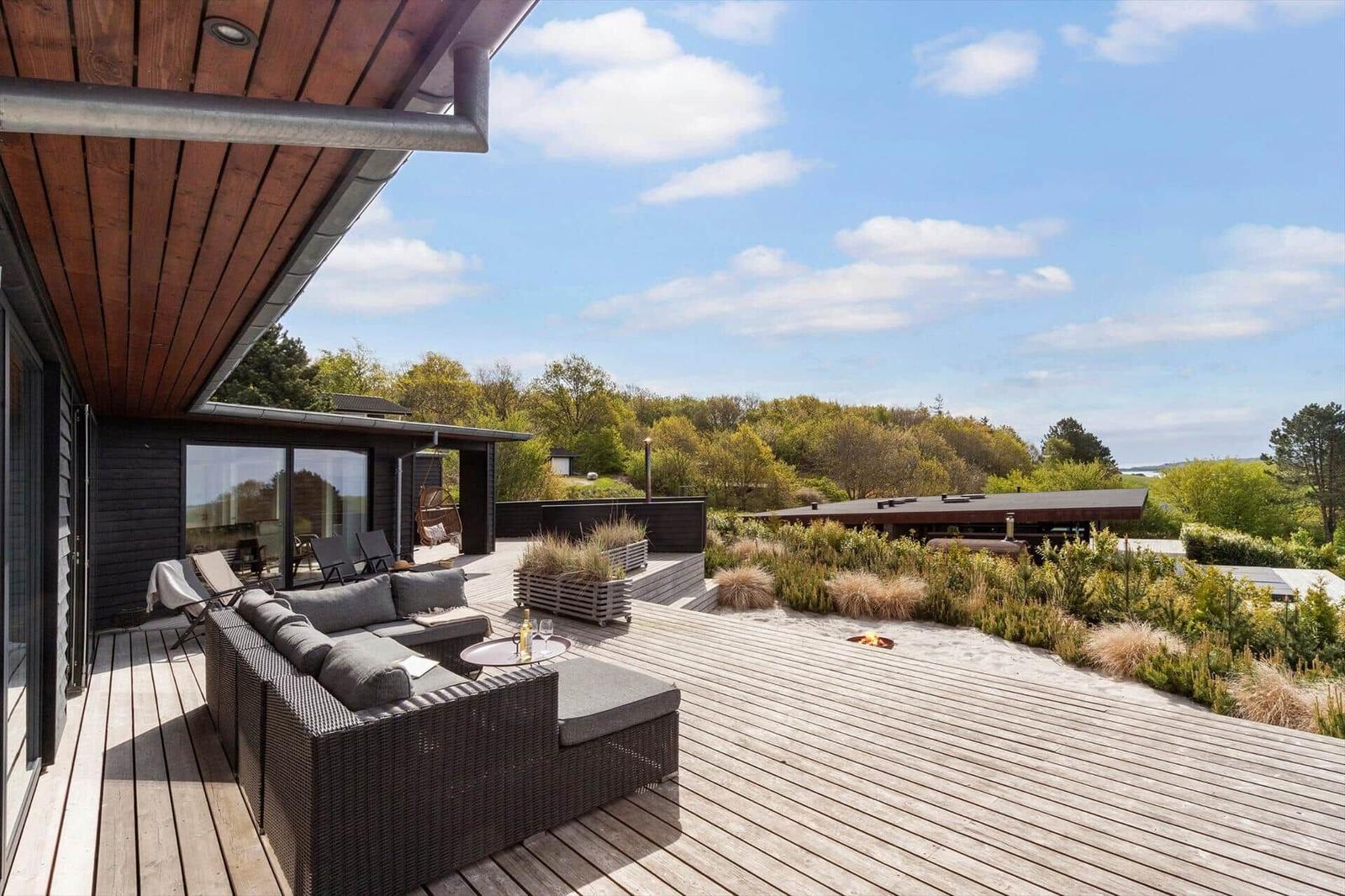 Terrasse mit Sitzgruppe, Grillbereich und Blick auf Wald.