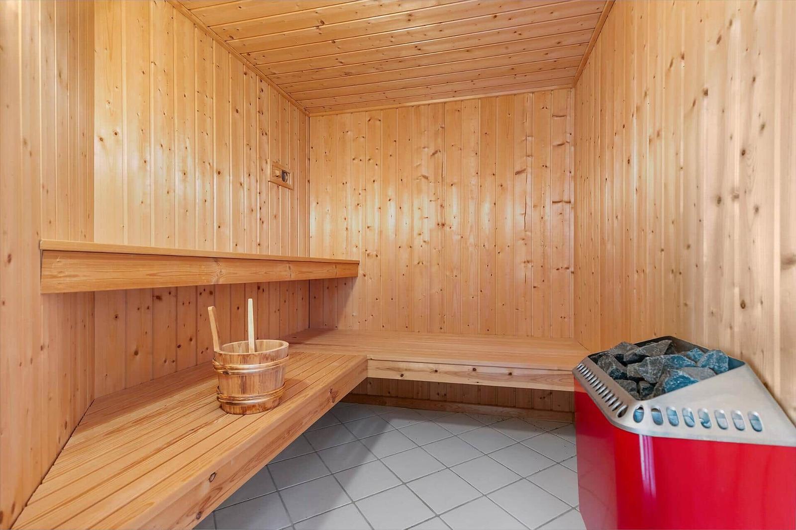 Sauna mit Holzbank, Holzwanne und Steinkachelofen.