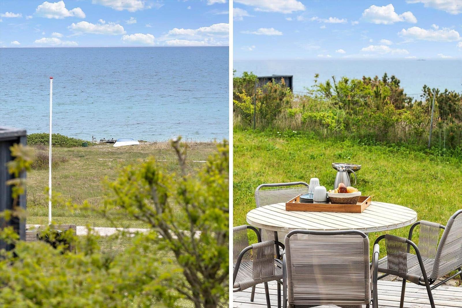 Terrasse mit Tisch und Stühlen, Blick auf Meer und Grünflächen.