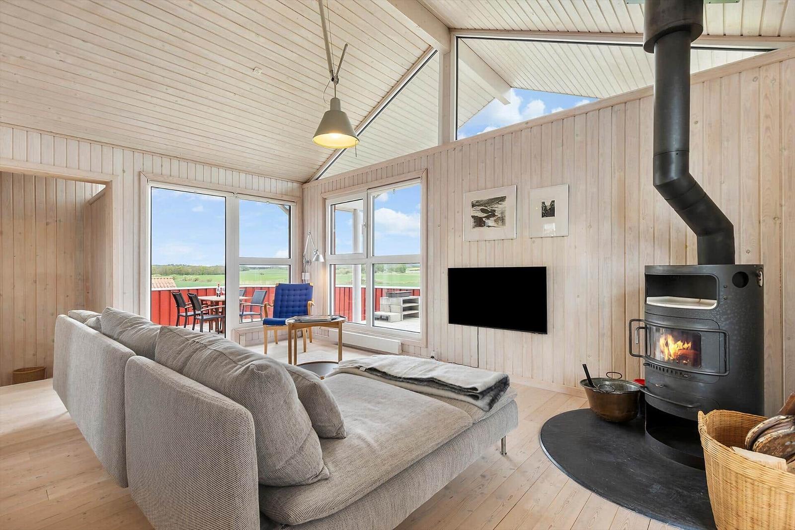 Wohnzimmer mit Kamin, Sofa und Blick auf Terrasse.