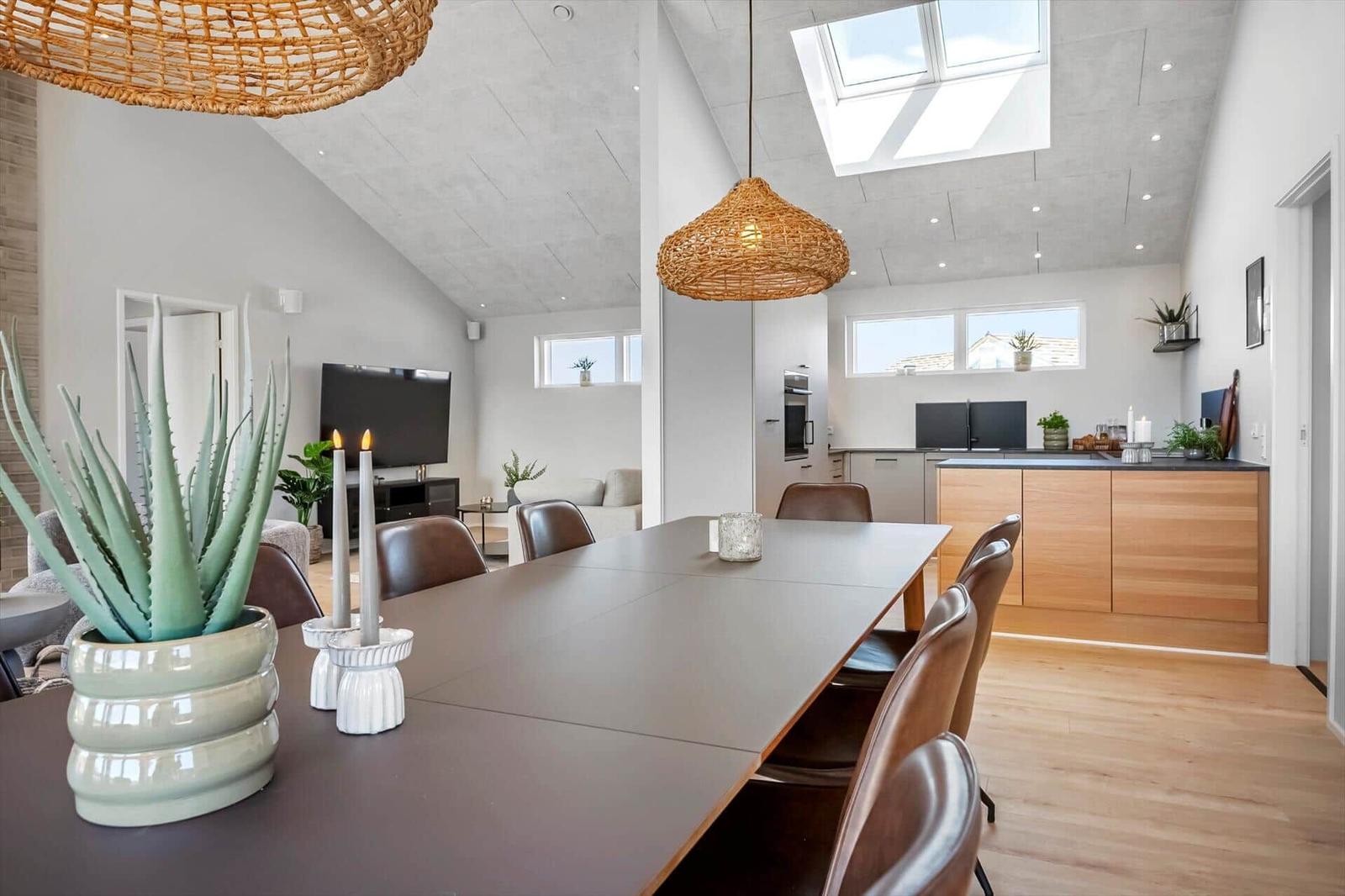 Dining room with table, chairs, and skylight. Kitchen with wooden cabinets and countertop.