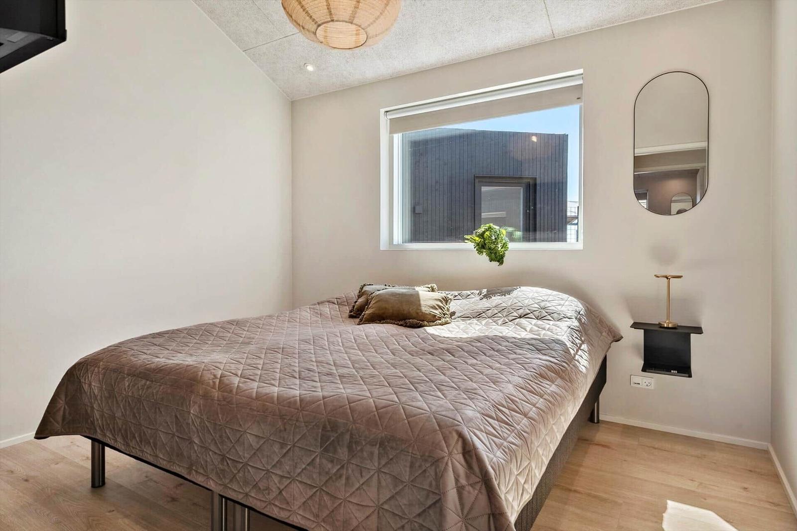 Bedroom with bed, window, and mirror on the wall.