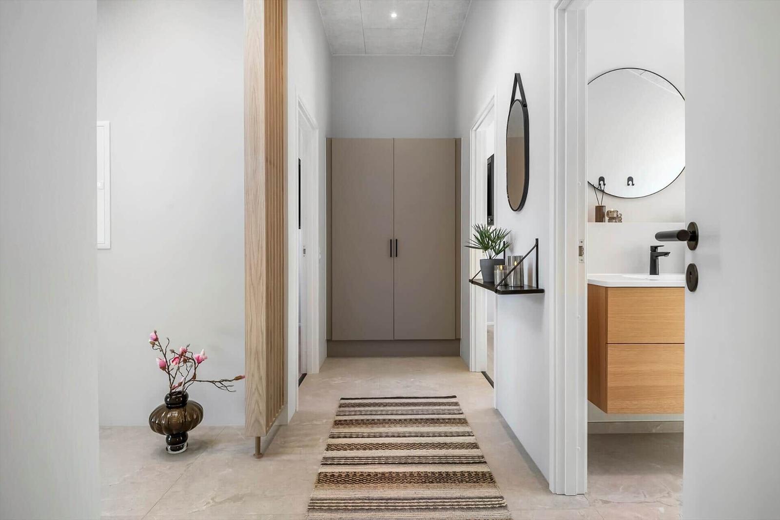 Hallway with wardrobe, bathroom, and tiled floor. Decorative vase and mirror visible.