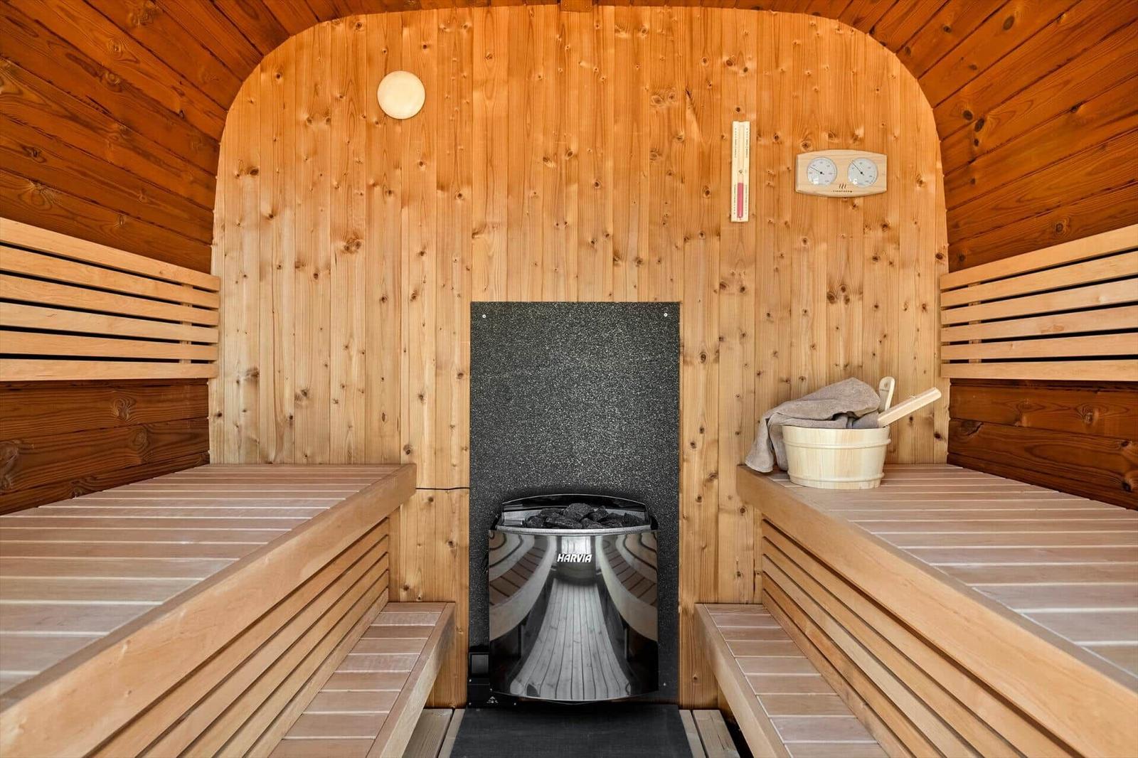 Sauna with wooden benches, stove, and bucket.