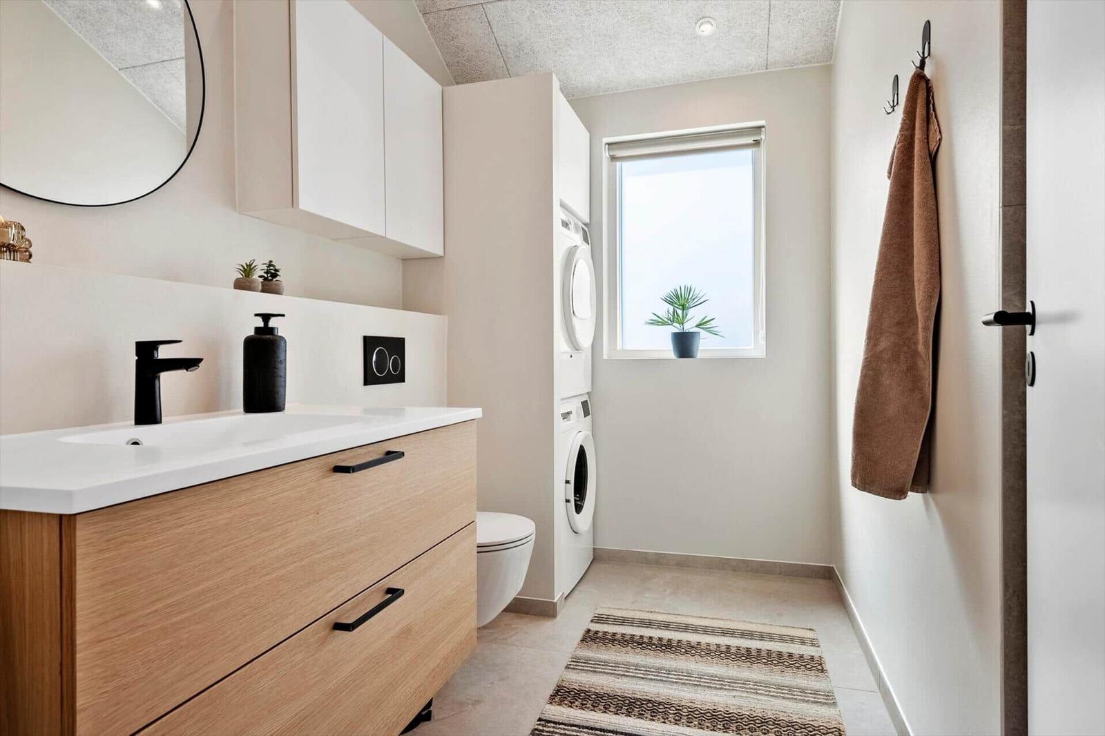 Bathroom with sink, mirror, toilet, and washer dryer.