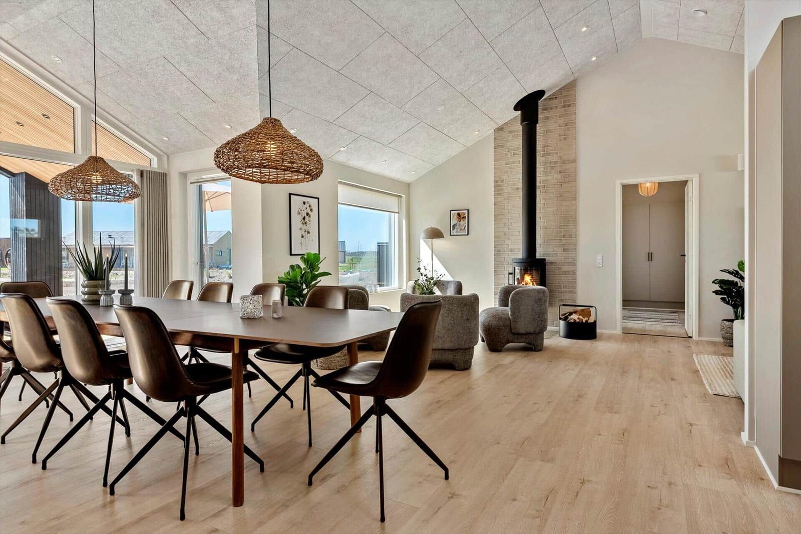 Dining area with table and chairs, fireplace, and large windows with outdoor view.