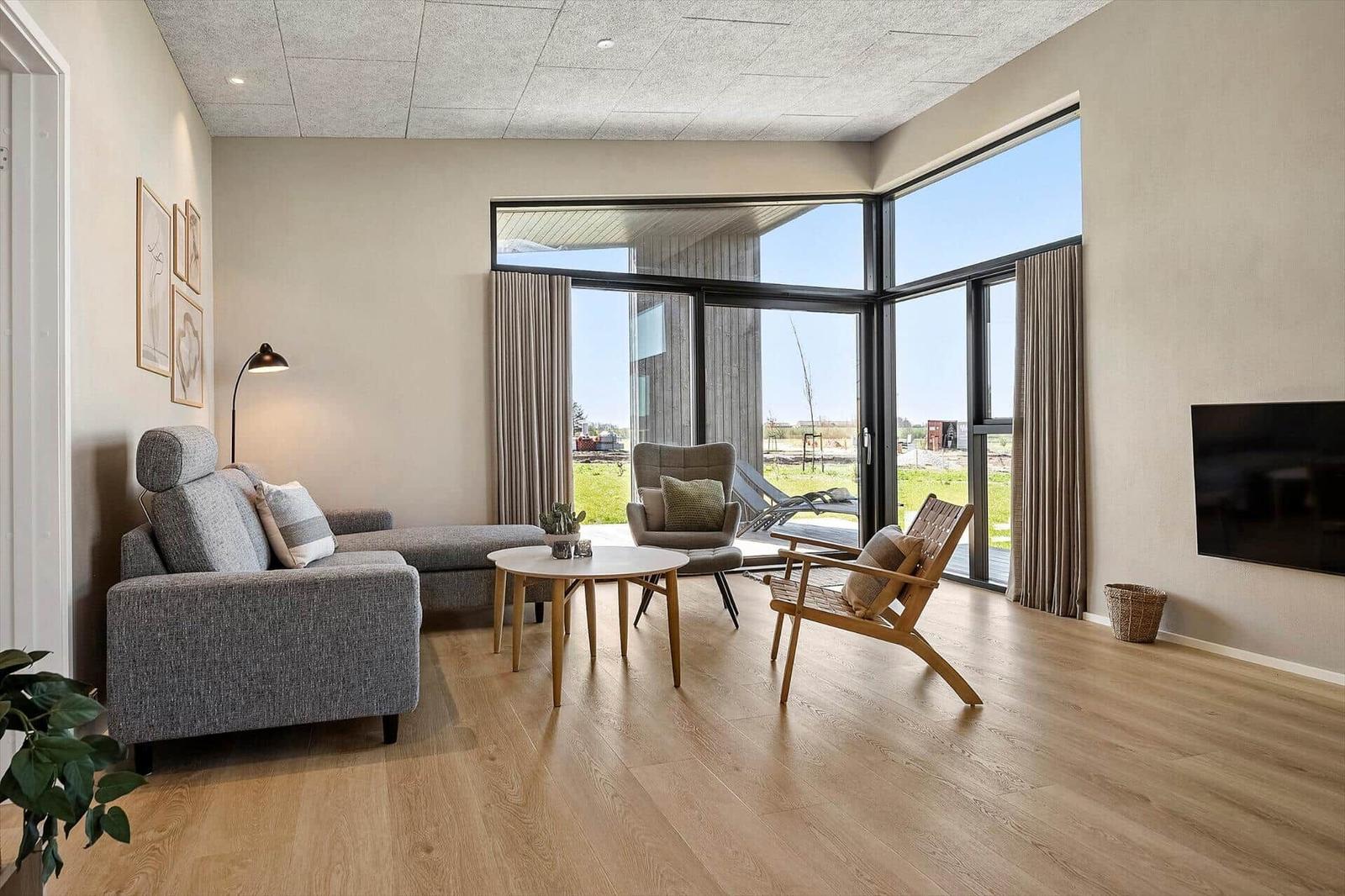 Living room with sofa, chairs, and large window to terrace.