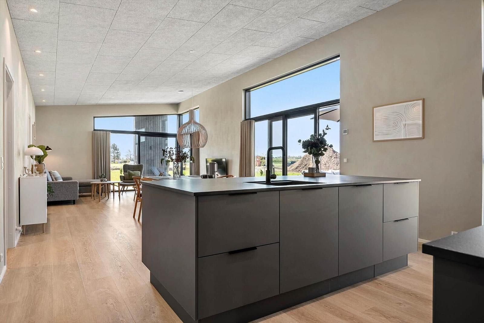 Kitchen with island and large window. Living area with sofa and table.