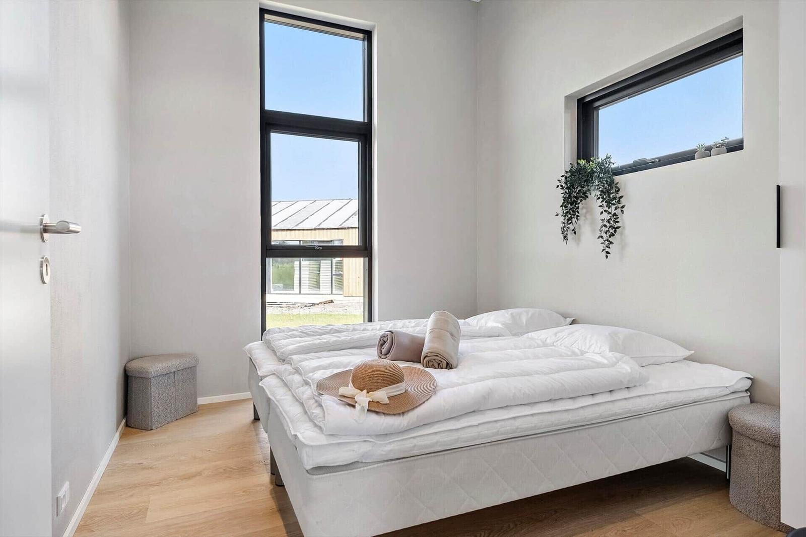 Bedroom with large window, bed, and plant on the wall.