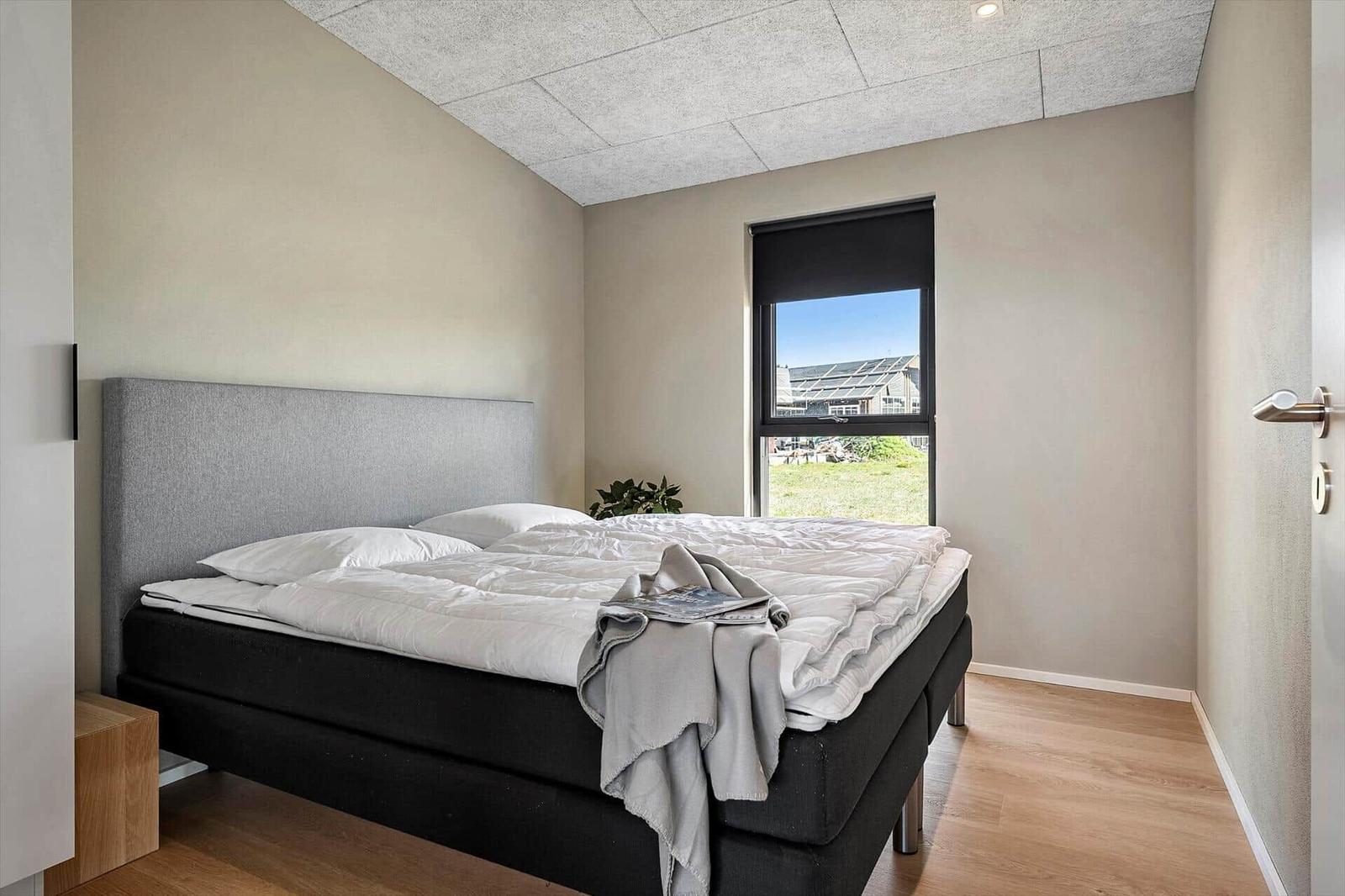 Bedroom with bed, window, and wooden floor.