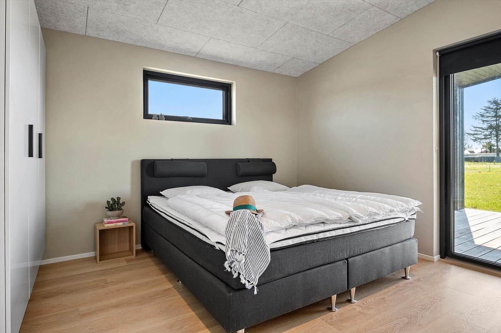 Bedroom with double bed, small nightstand, and window. Access to terrace.