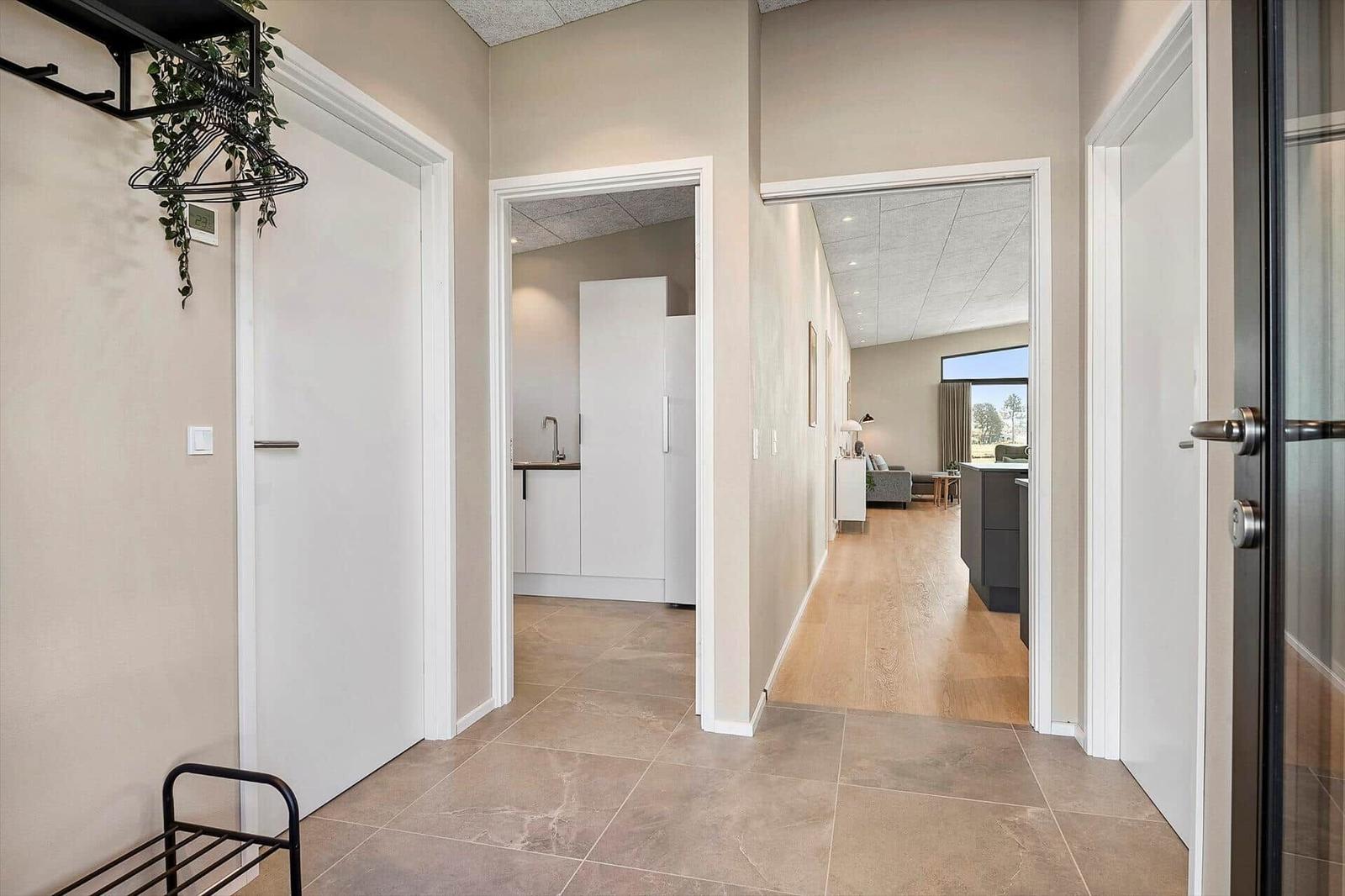 Hallway with view into kitchen and living room. Wooden and tile flooring.