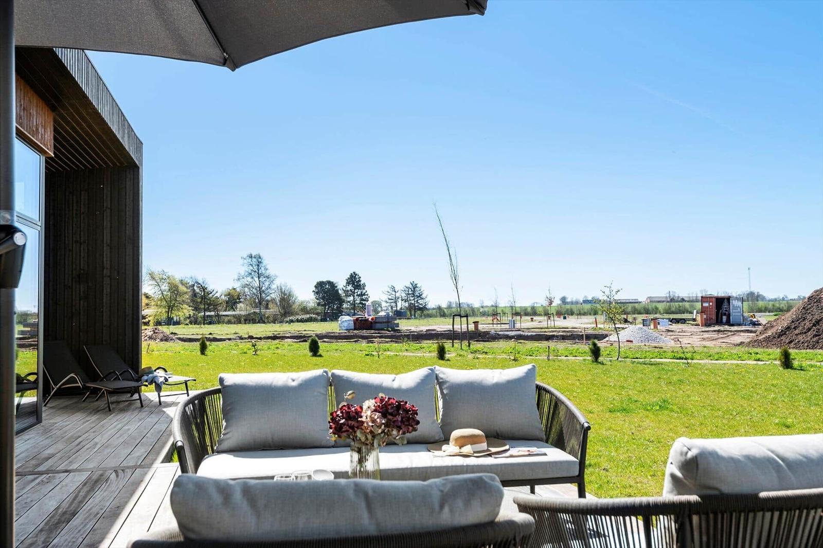 Terrace with seating and view of green field under clear sky.