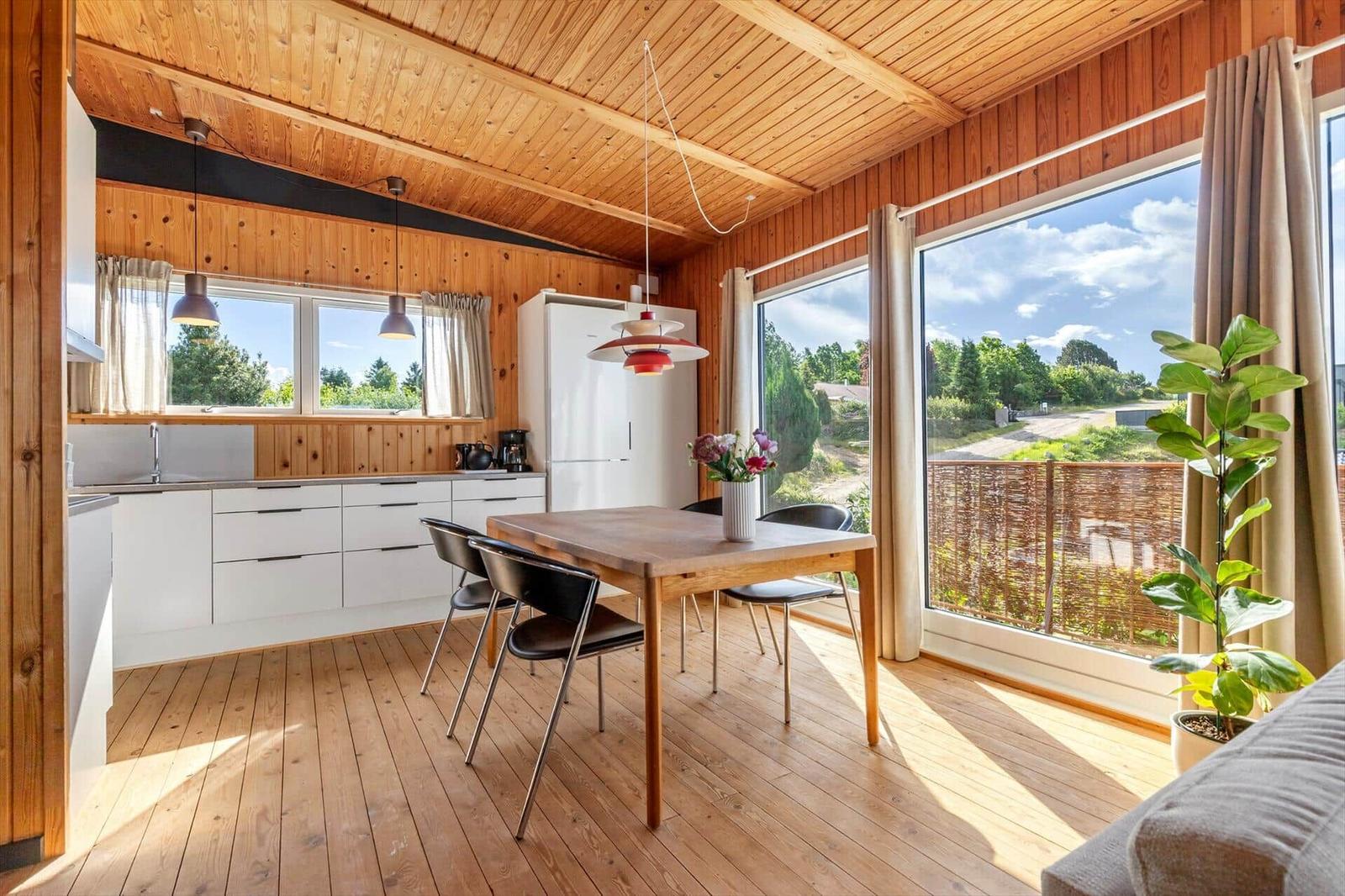 Kitchen and dining area with wooden ceiling, large windows, and view of the surroundings.