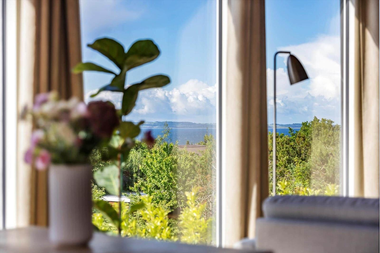 Through the window, you can see the sea and green trees.