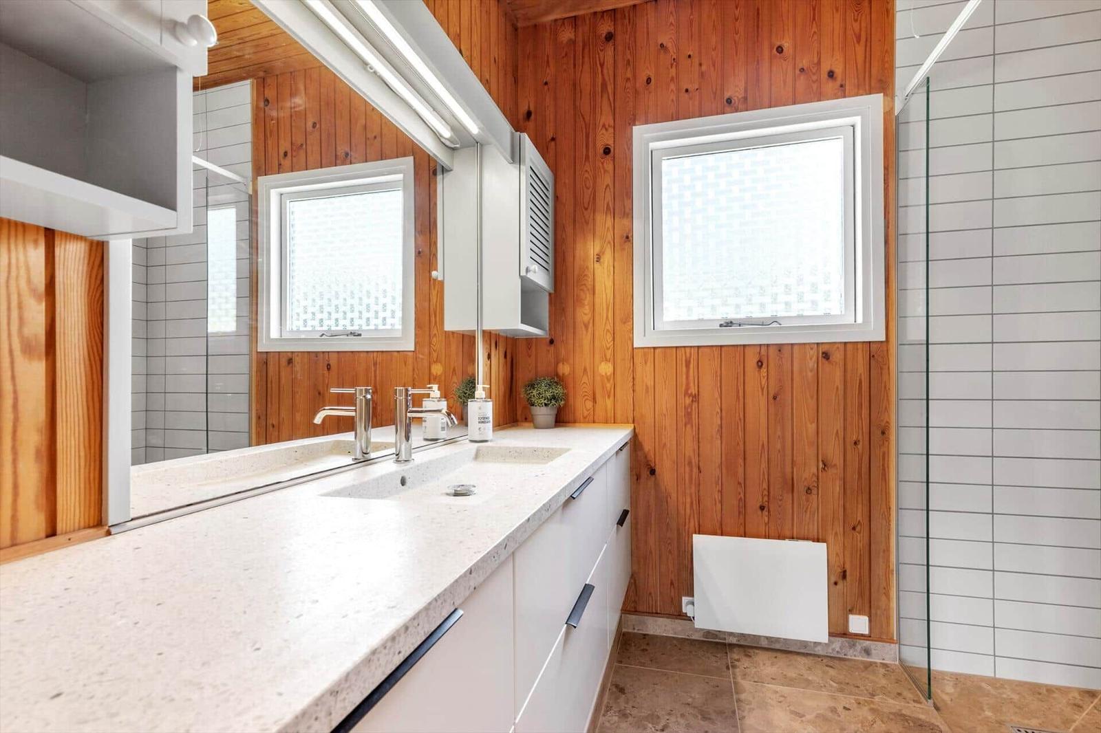 Bathroom with wooden wall, sink, and shower with glass enclosure.
