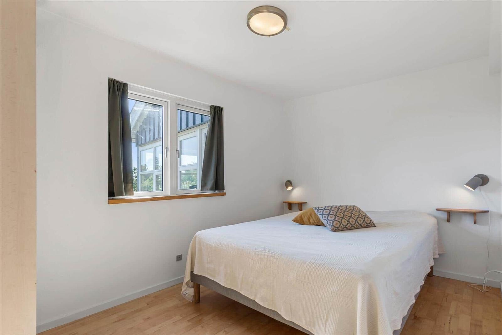 Ein Schlafzimmer mit einem Bett, einem Fenster und zwei Wandlampen.