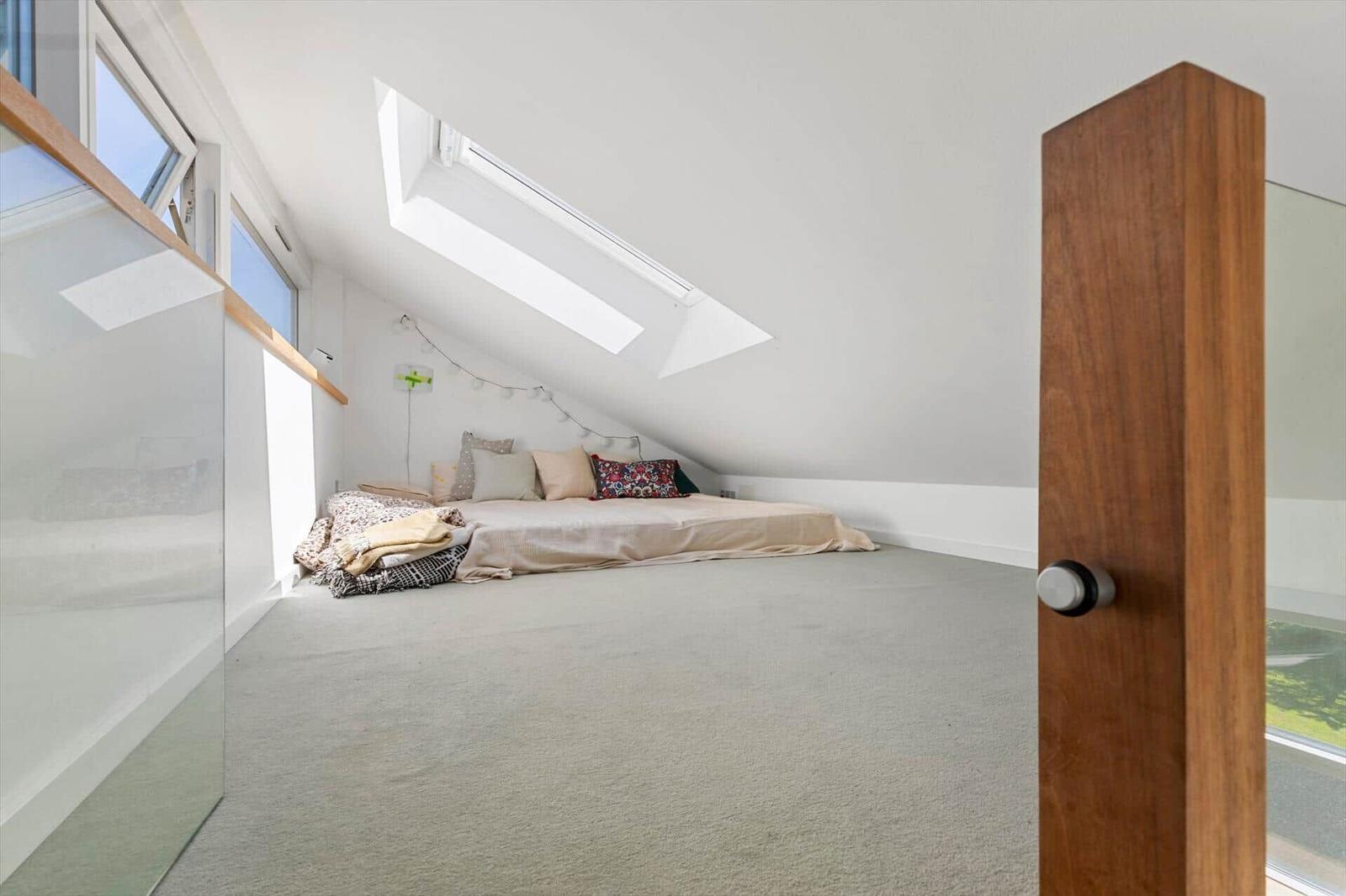 Schlafzimmer mit Dachschräge, Dachfenster und Bett an der Wand.