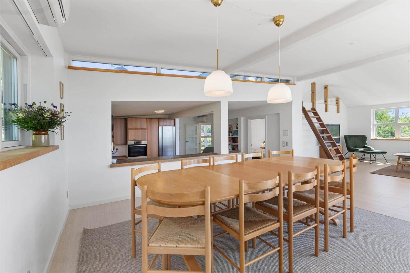 Esszimmer mit Holztisch, Stühlen und Blick in Küche und Wohnbereich.