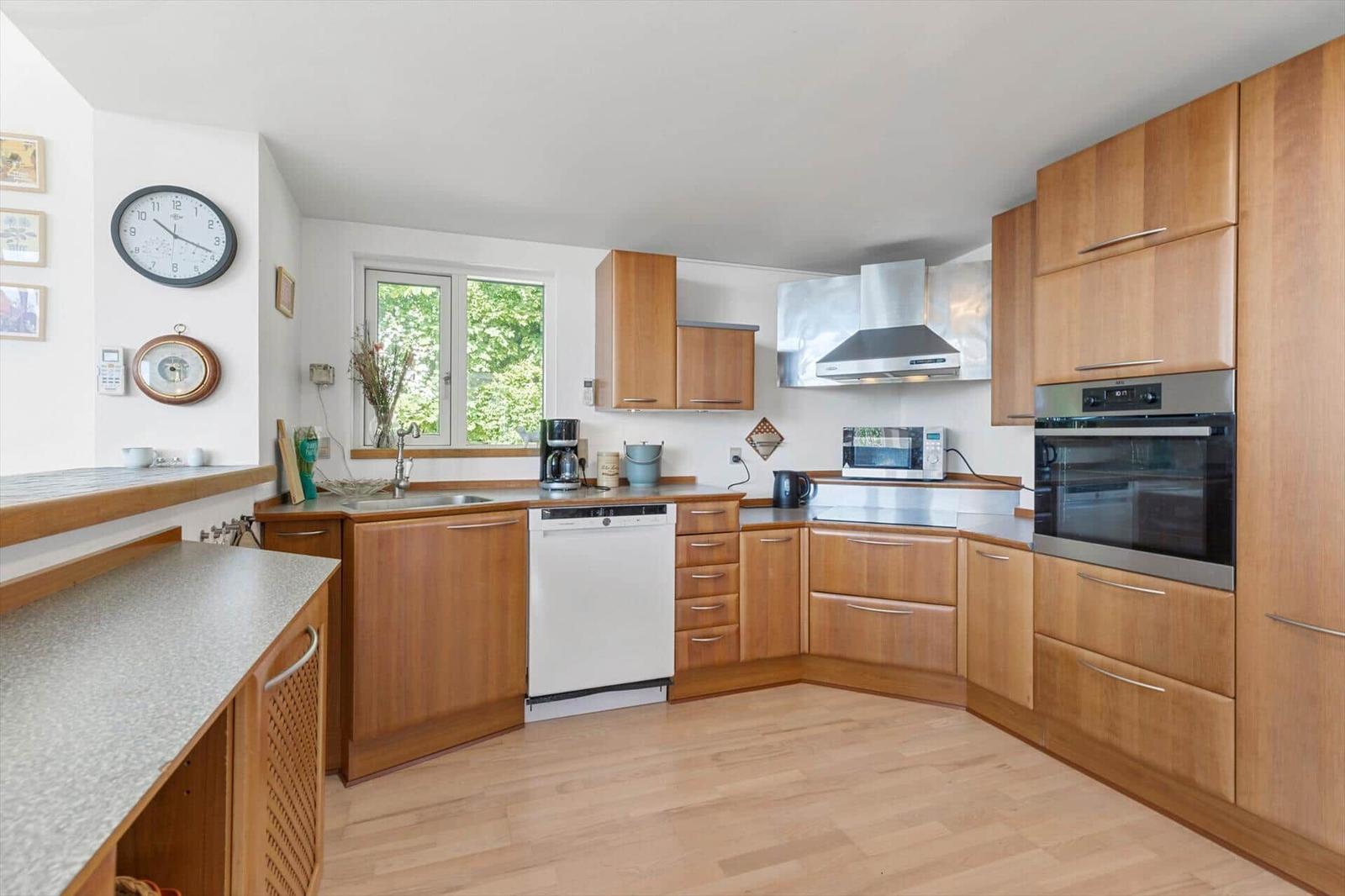 Küche mit Holzschränken, Spüle, Waschmaschine und Backofen.