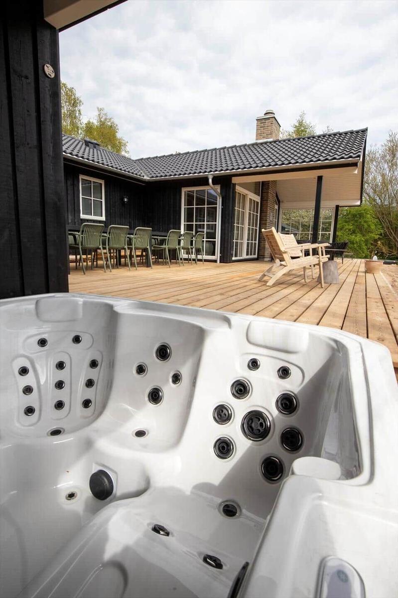 Hot tub on terrace with view of house and garden