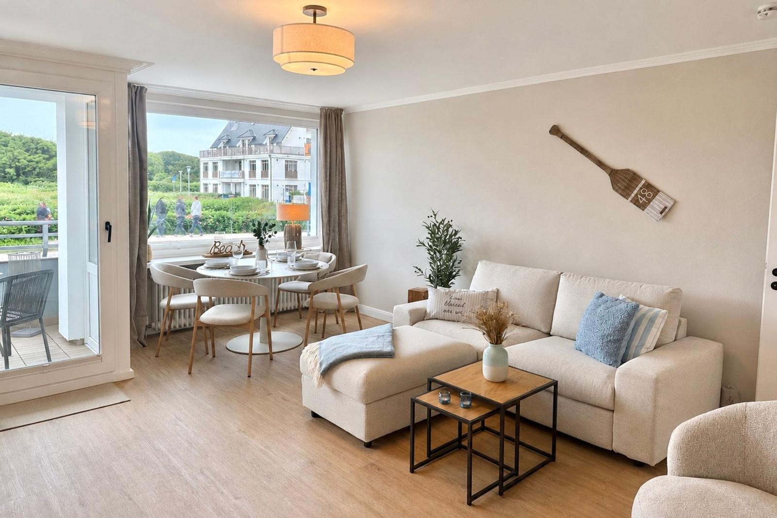 Wohn- und Essbereich mit Sofa, Tisch und Blick auf Balkon und Außenbereich.