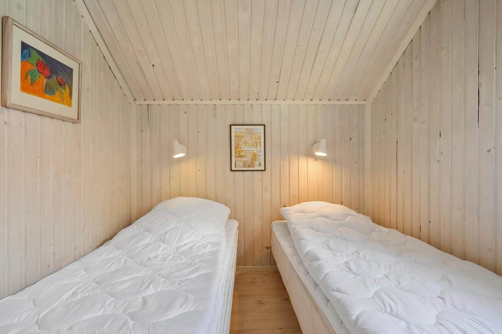 Zwei Betten in einem Zimmer mit Holzwandverkleidung und Deckenbalken.