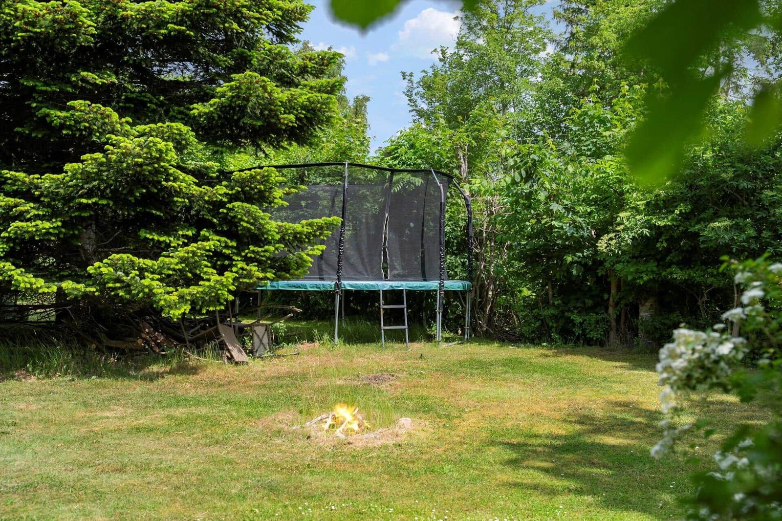 Hinterhof mit Trampolin und kleinem Feuer im Gras.