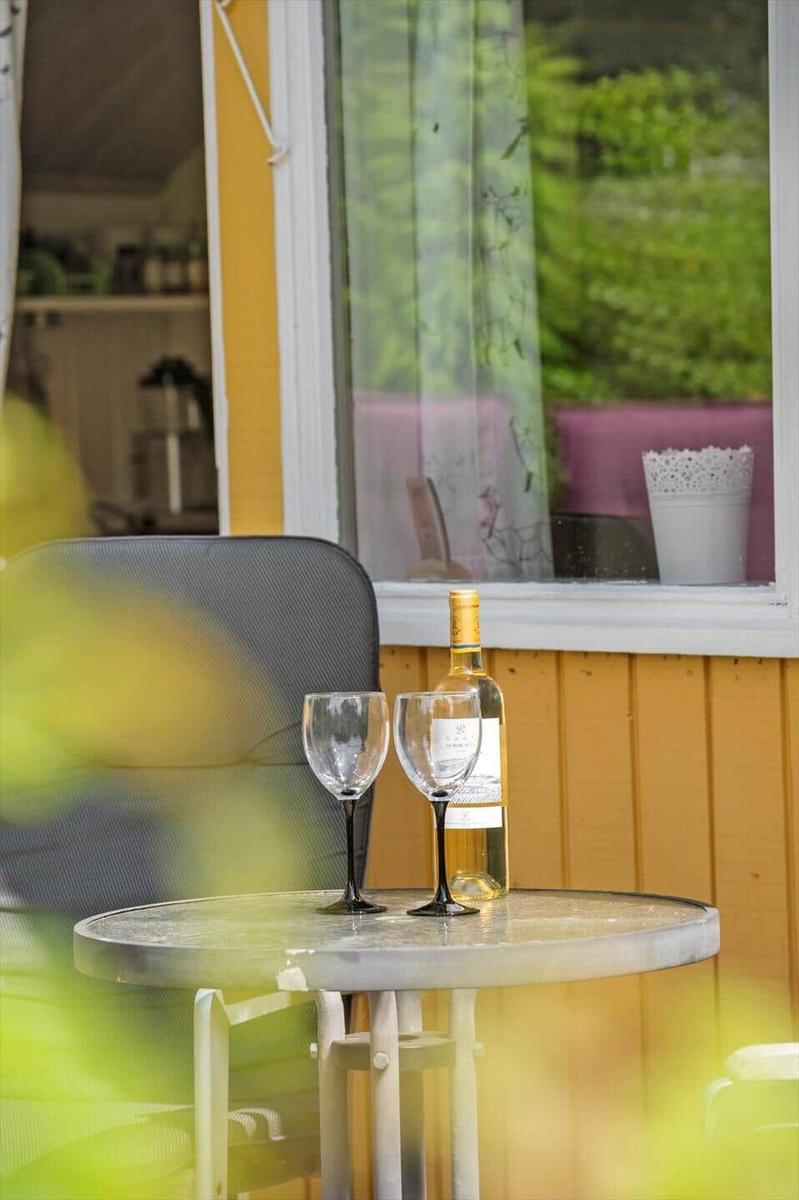 Ein Tisch mit Weinflasche und Gläsern vor einem Fenster mit Blick auf grüne Pflanzen.