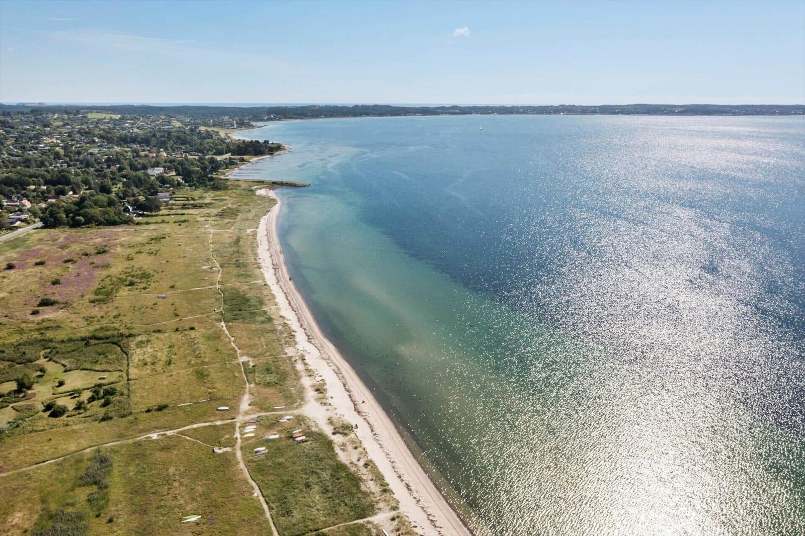 Aerial view of a coastal area with beach, water, and green landscape.