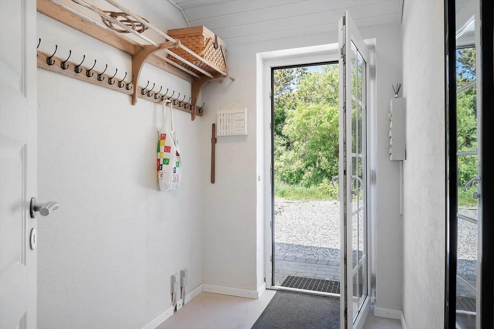 Eingangsbereich mit Hakenwand, Korb und Tür zum Außenbereich.