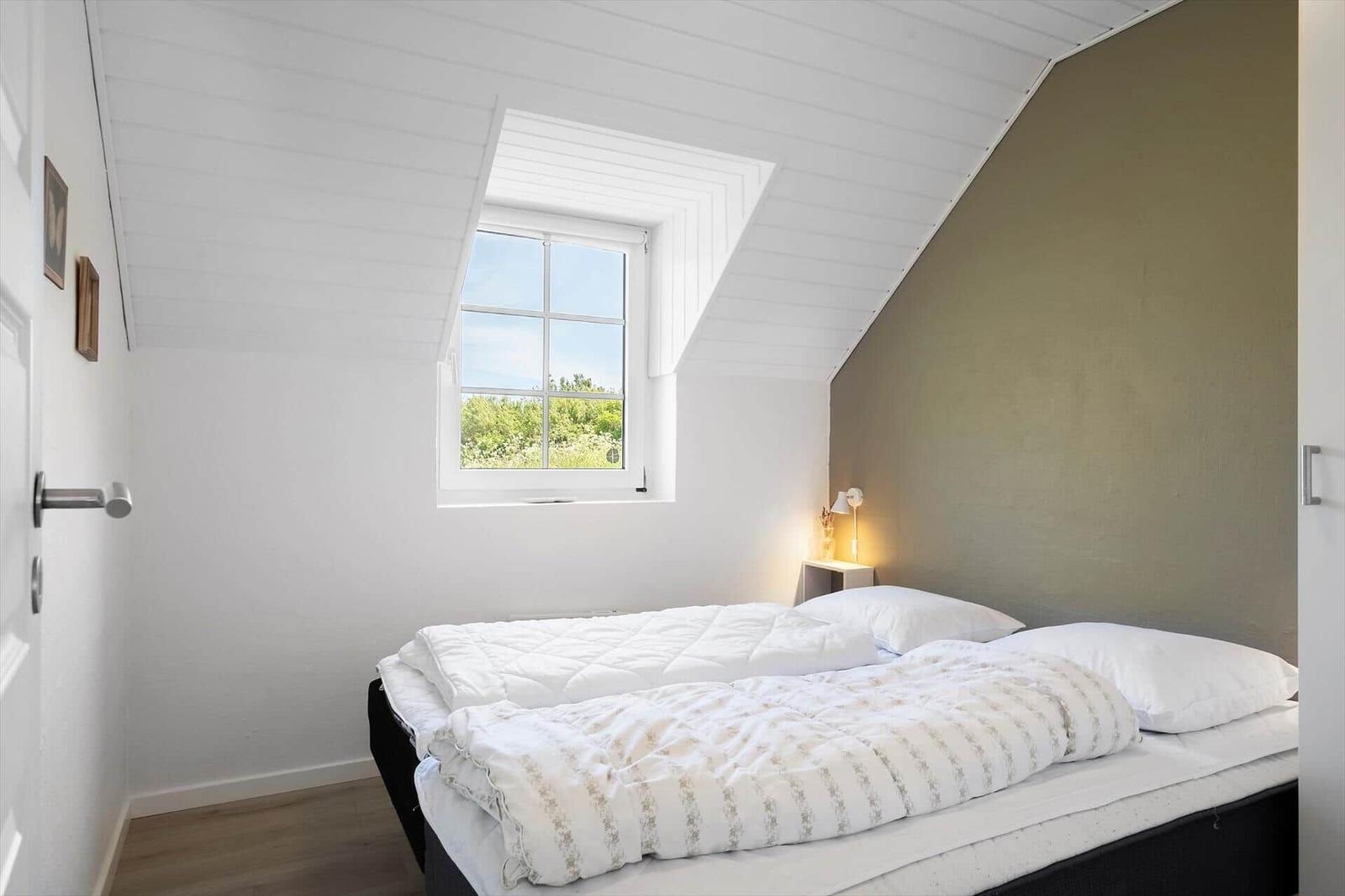 Schlafzimmer mit Dachfenster, Bett und Nachttisch.