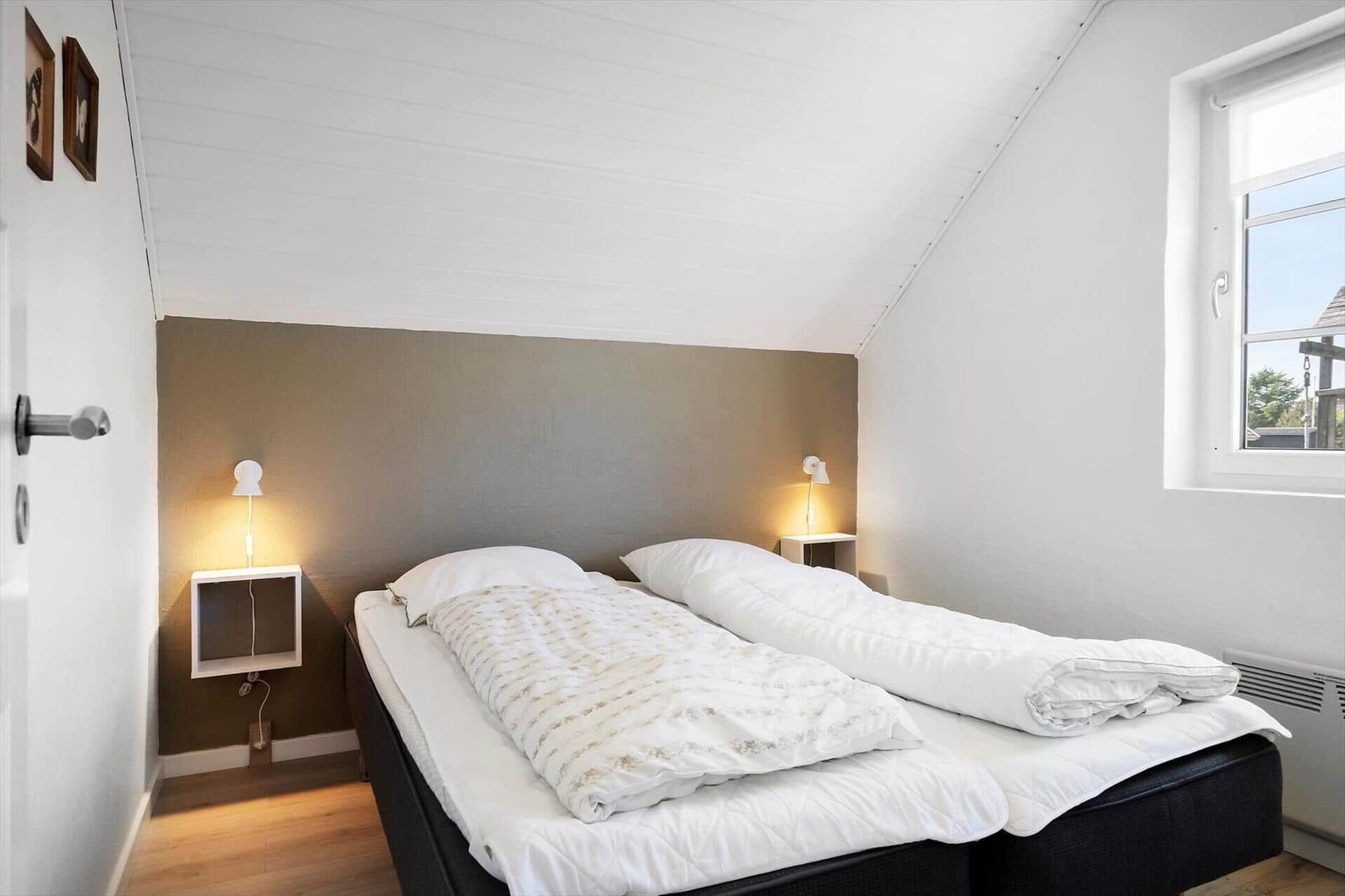 Schlafzimmer mit Doppelbett, Nachttischen und Fenster.