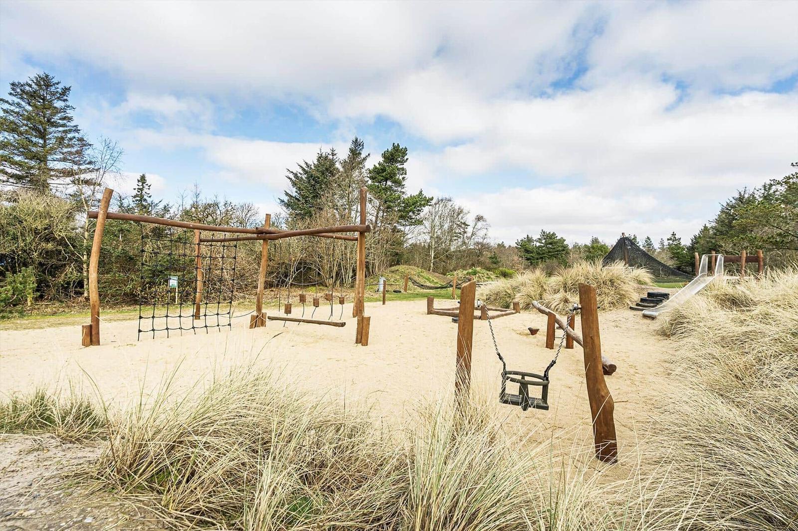Spielplatz mit Sand, Schaukel und Rutsche in natürlicher Umgebung