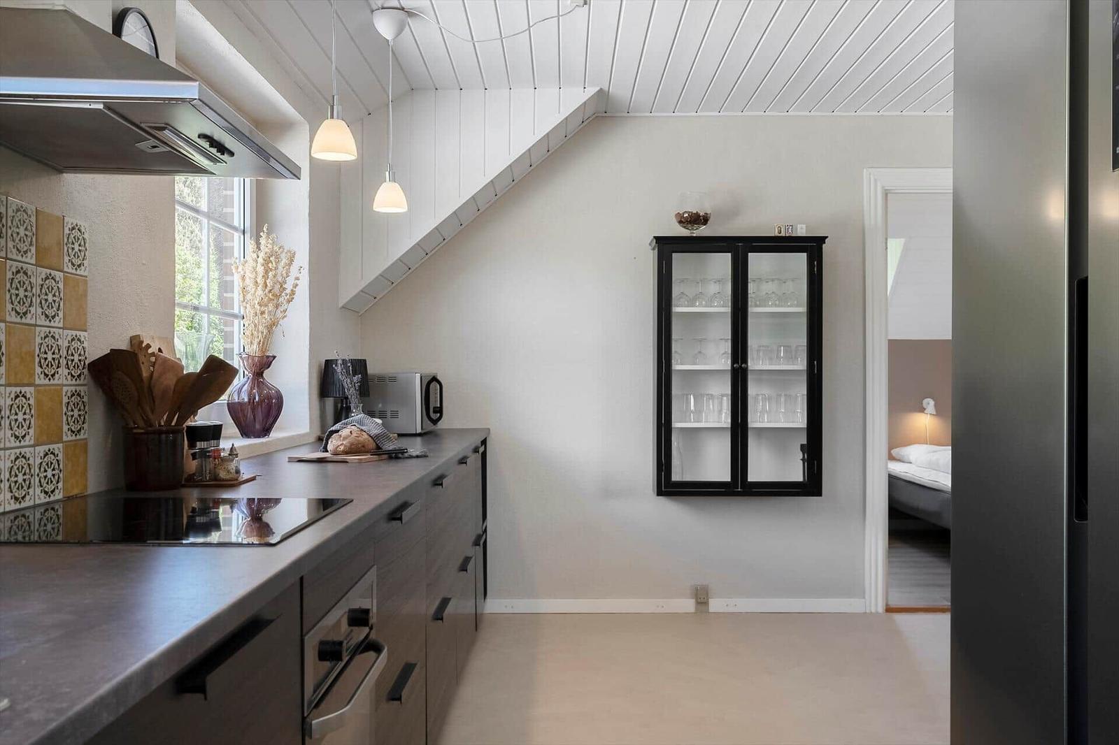 Küche mit Arbeitsplatte, Dunstabzug und Glasvitrine an der Wand