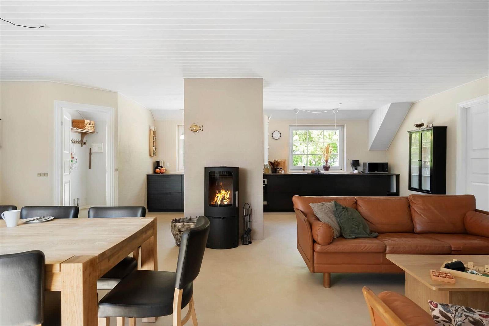Wohn- und Essbereich mit Kamin, braunem Sofa und Holztisch.